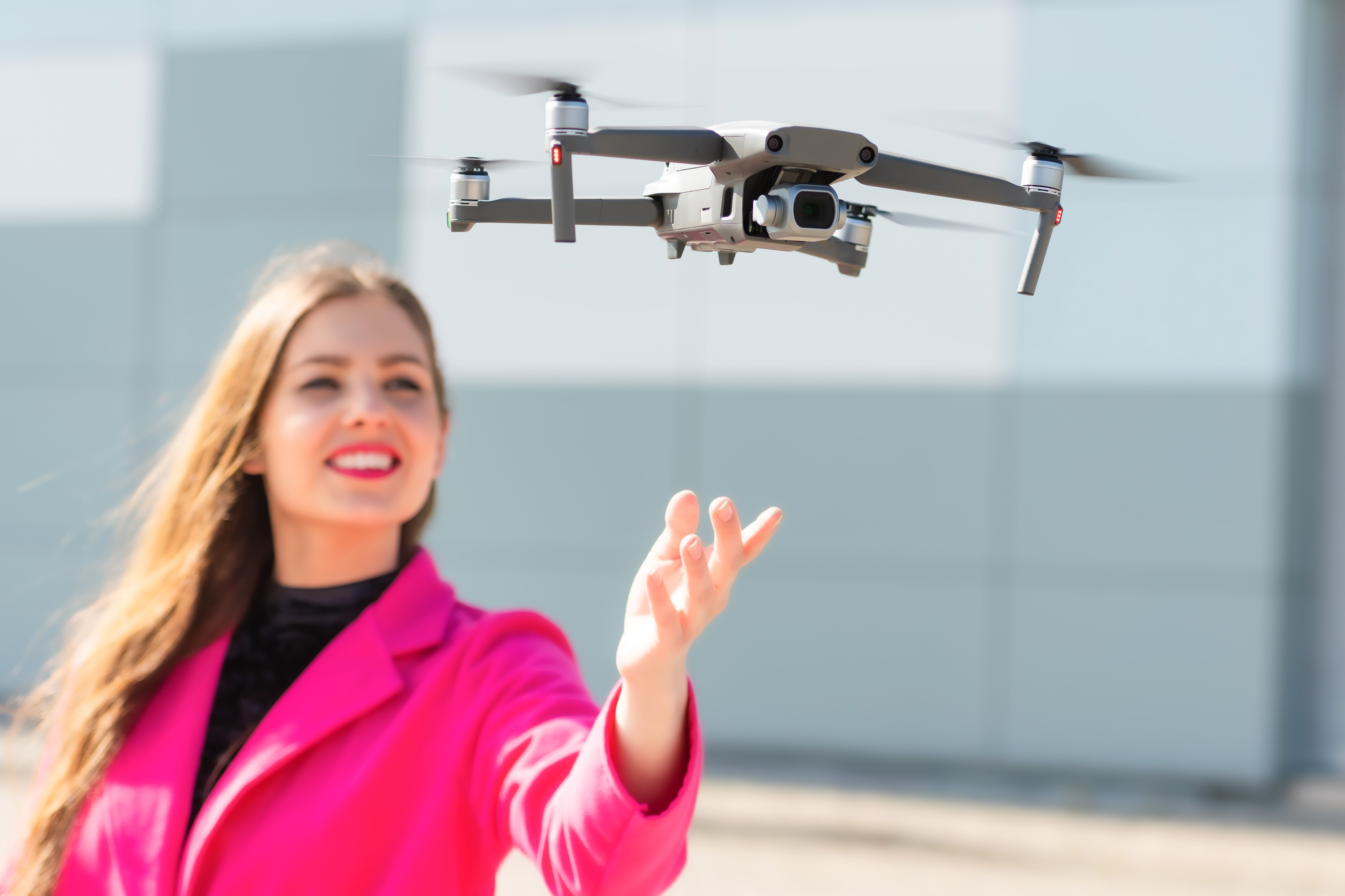 Start the drone, launching from hands. Defocused young woman in
